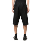 Maison Margiela black linen Bermuda shorts displayed on a hanger, showcasing a relaxed fit and clean design.