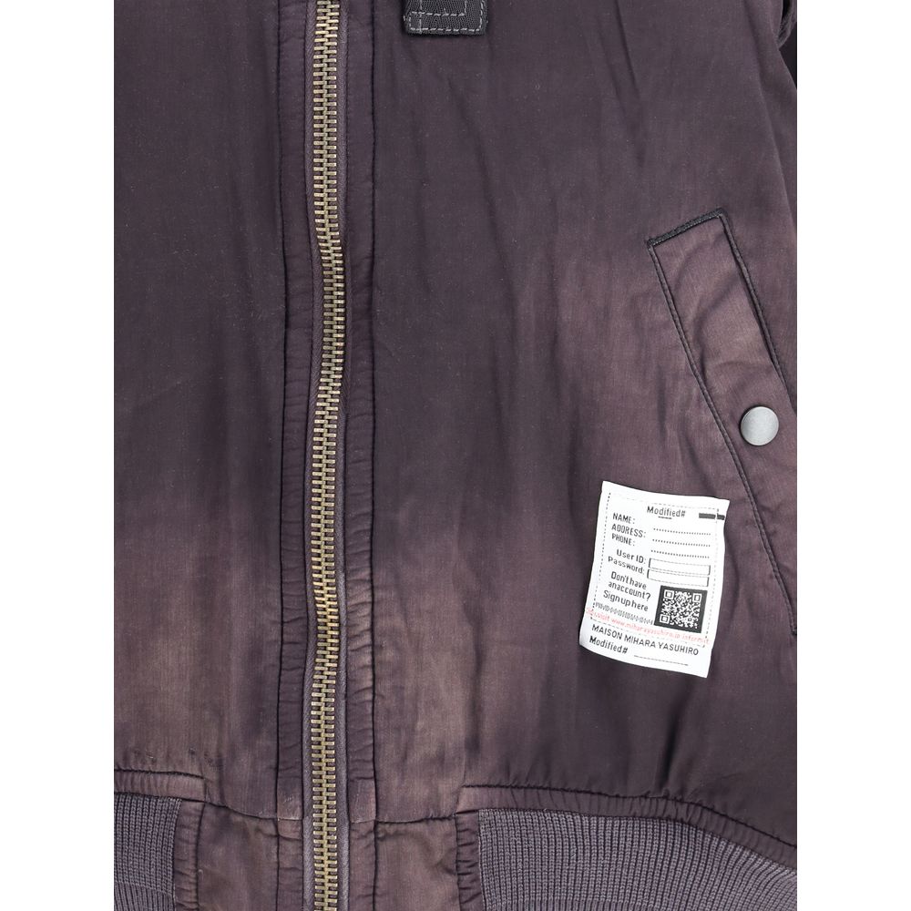 Black rayon bomber jacket by Maison Mihara Yasuhiro with a sleek design and ribbed cuffs, shown on a hanger.