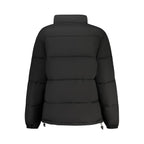Black Guess Jeans women's polyester jacket with a fitted design, shown on a model standing outdoors.