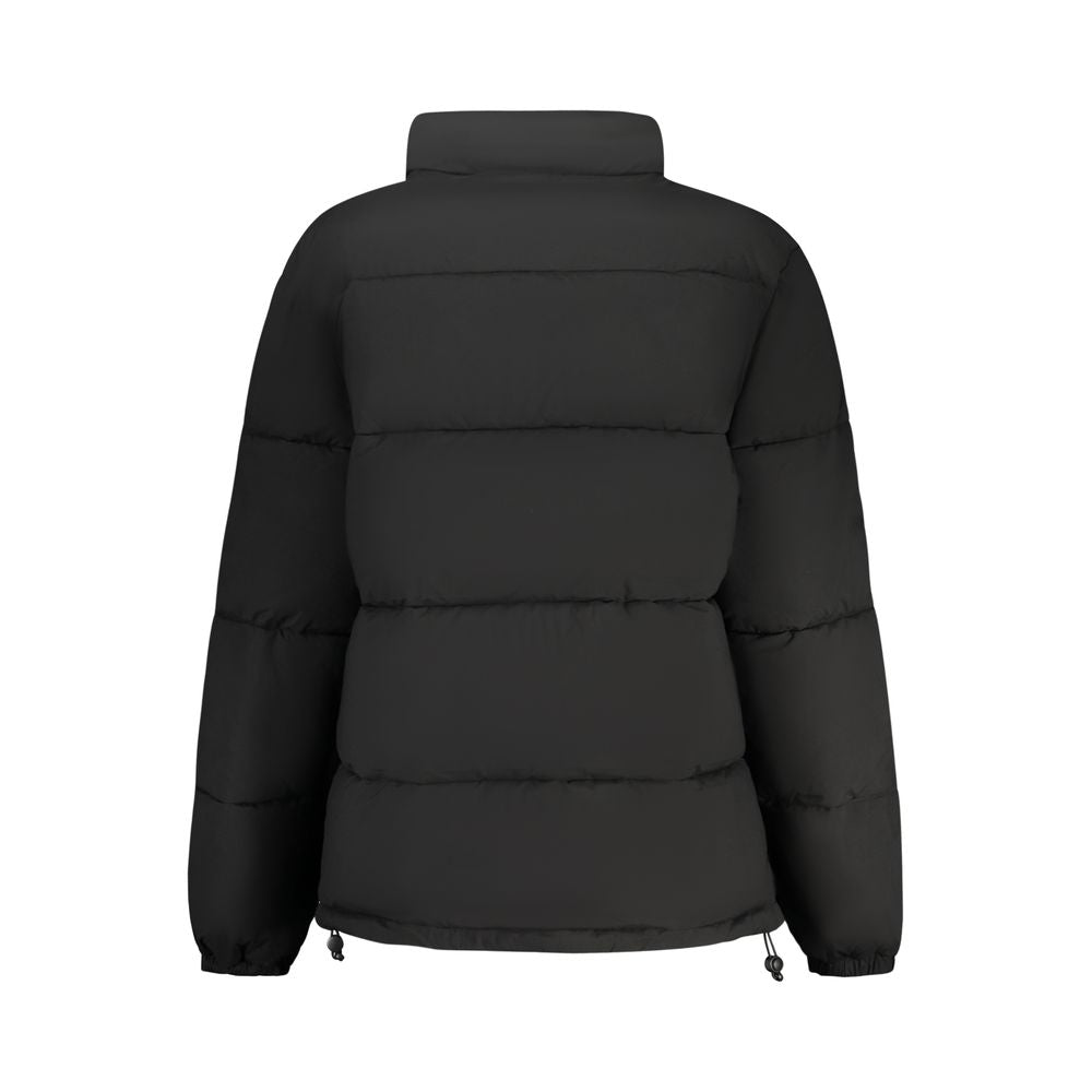 Black Guess Jeans women's polyester jacket with a fitted design, shown on a model standing outdoors.