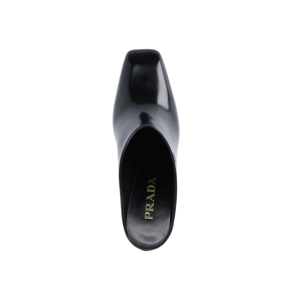 Prada black calfskin mules with pointed toe and sleek design, featuring a smooth leather finish and stylish slip-on style.