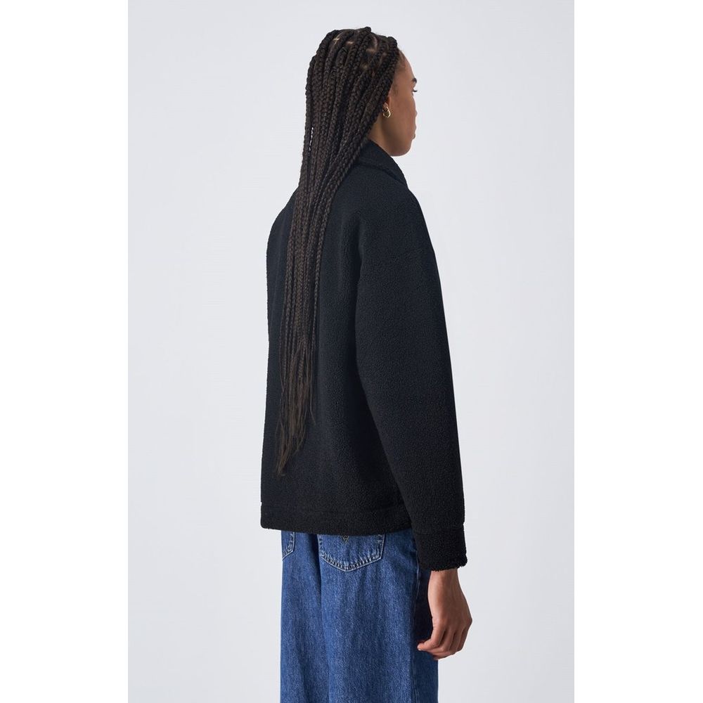 Champion black polyester full-length jacket displayed on a hanger, showcasing its sleek design and smooth fabric.
