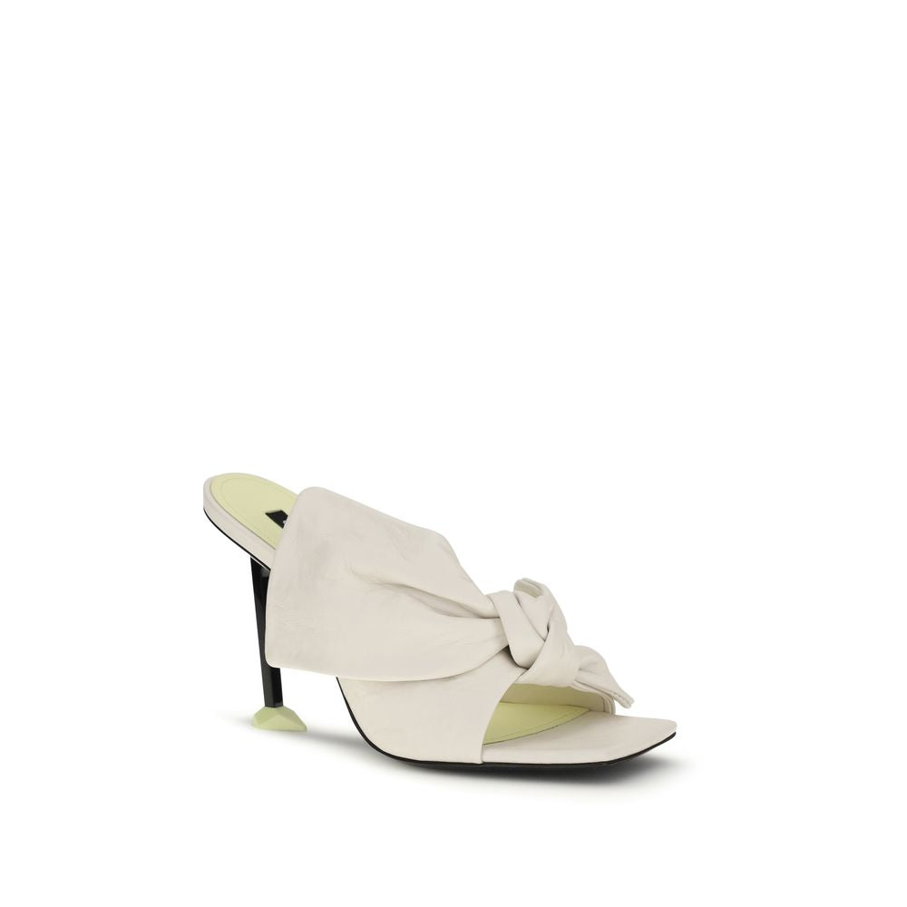 Givenchy white lamb Ovis Aries mules with sleek design and pointed toe, outdoor setting showcasing stylish luxury footwear.