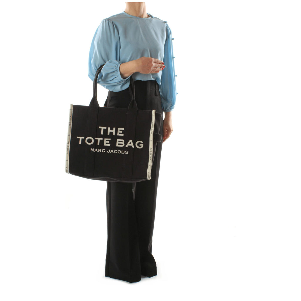 Black fabric shoulder bag by Marc Jacobs with adjustable strap and minimalist design, ideal for everyday use.