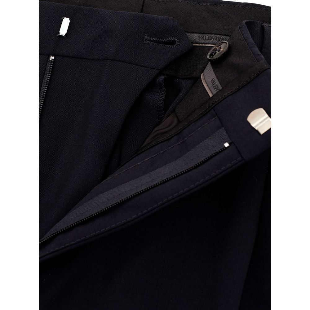 Black wool dress pants by Valentino Garavani, tailored fit with sleek style, shown on a hanger against a plain background.