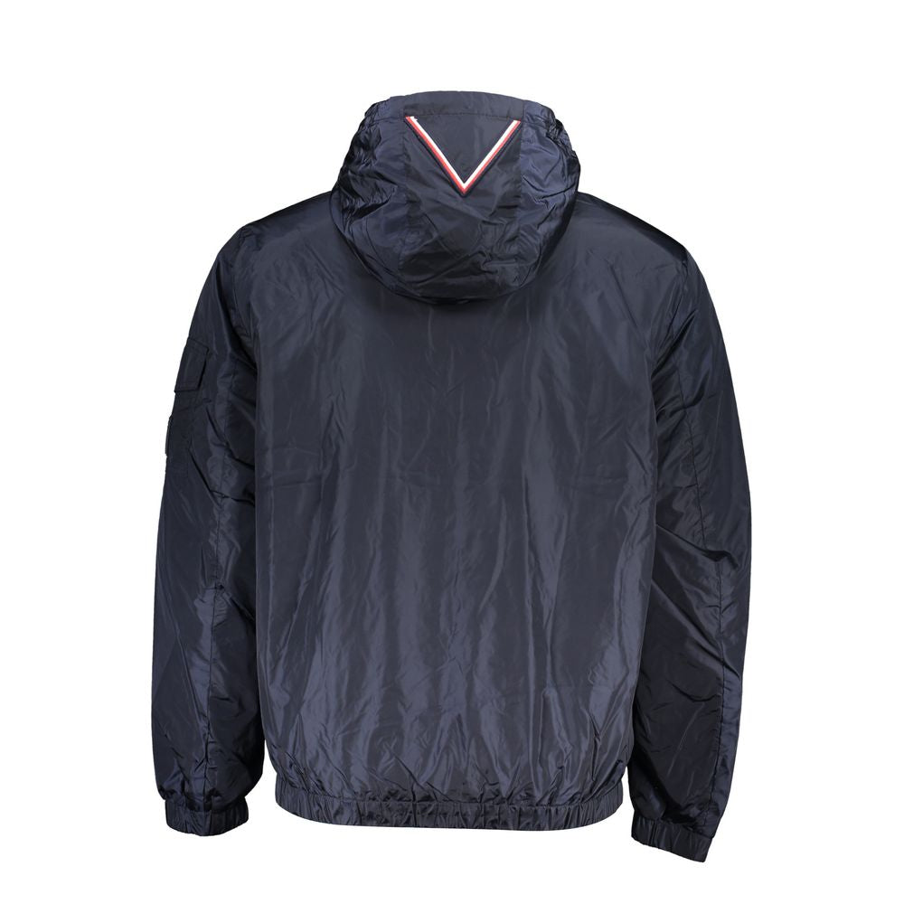 Tommy Hilfiger men's blue nylon jacket displayed on a hanger, featuring a zip front, collar, and brand logo details.