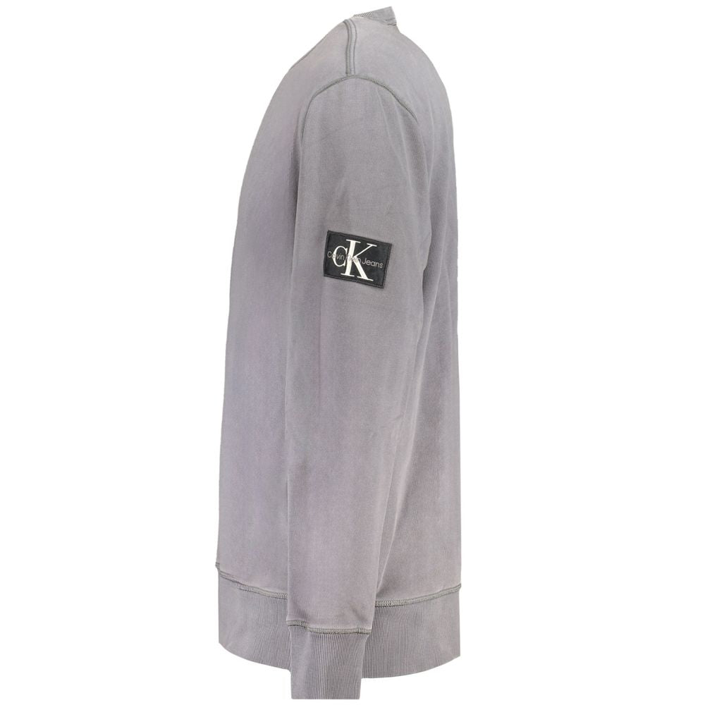Calvin Klein gray cotton men's sweater displayed on a plain background, showing the classic crewneck design and soft fabric texture.