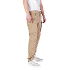 Replay beige cotton cargo pants with multiple pockets and relaxed fit, shown on a model in a casual outdoor setting.