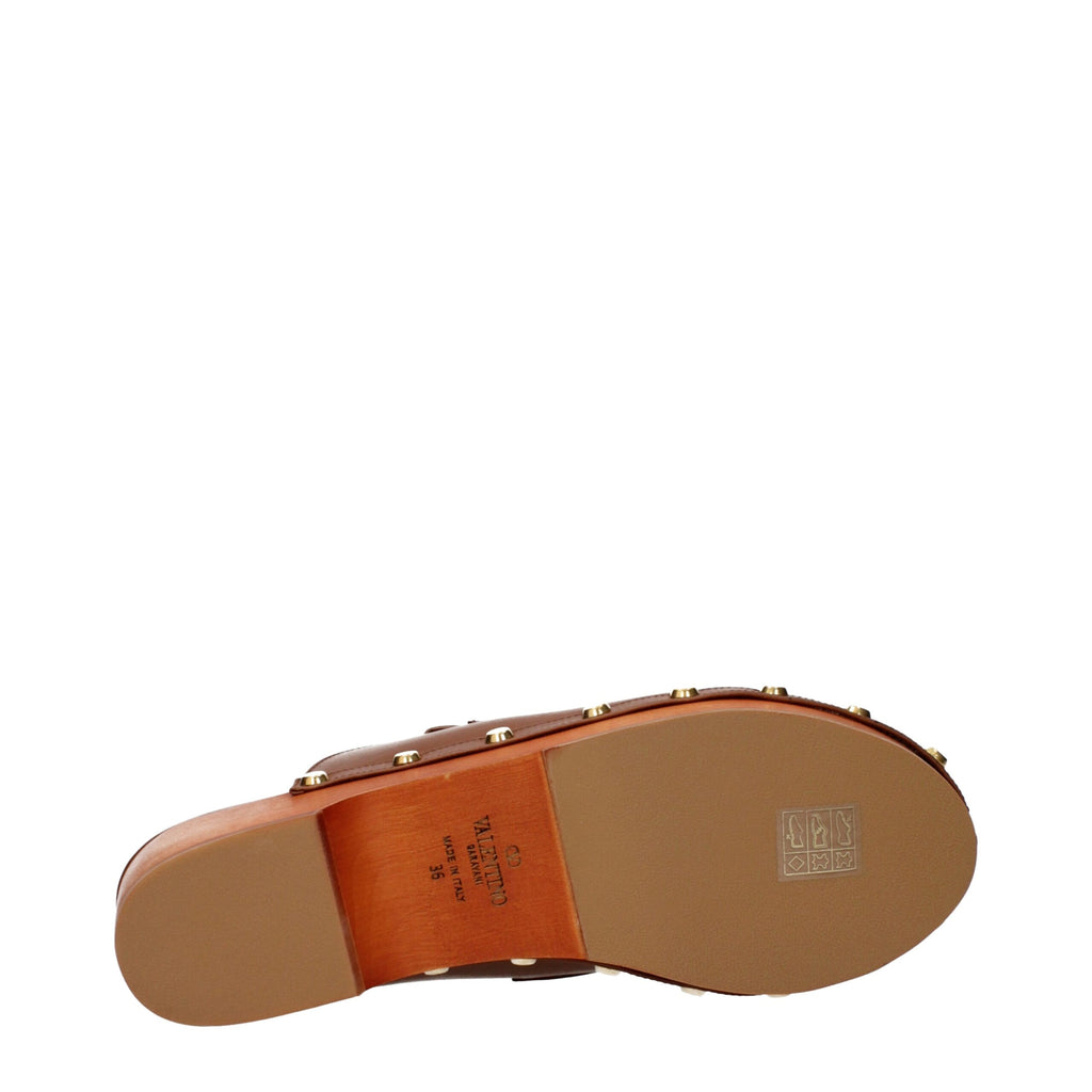 Brown leather slippers by Valentino Garavani featuring a sleek design and classic stitching, perfect for casual or elegant wear.